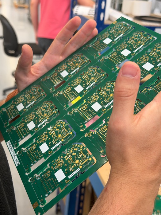 Bare Kode Dot main PCB panels, fresh from fabrication, held in two hands